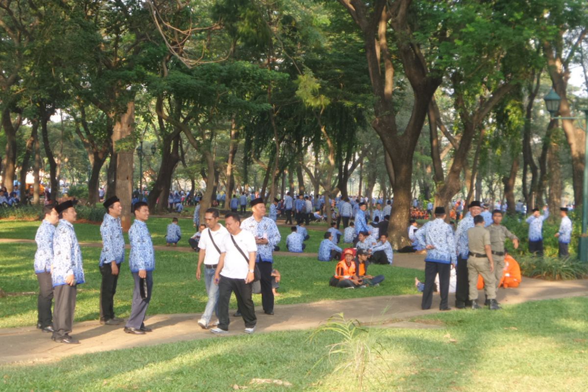 Sejumlah PNS di lingkungan Pemprov DKI tampak bersantai di bawah pohon saat sejumlah PNS lainnya melakukan upacara memperingari Hari Kebangkitan Nasional di silang Monas, Jakarta Pusat, Sabtu (20/5/2017)