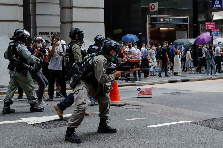 Seorang polisi anti huru-hara menembakkan senjatanya dalam demonstrasi yang berlangsung di Central, Hong Kong, di tengah pembahasan kedua aturan untuk menghukum penghina lagu kebangsaan China, pada 27 Mei 2020.