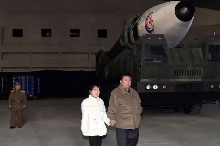 Kim Jong-un menggandeng tangan putrinya saat berfoto di depan rudal balistik.