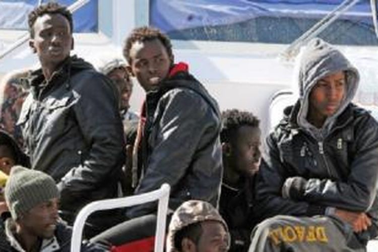 Sebagian imigran yang berhasil diselamatkan duduk di atas kapal Italia di pelabuhan Messina, Sabtu (18/4/2015).