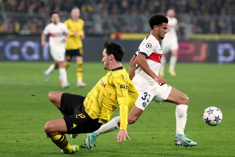 Gelandang Paris Saint-Germain (PSG), Warren Zaire Emery (kanan), melewati bek Borussia Dortmund, Mats Hummels, dalam laga terakhir Grup F Liga Champions 2023-2024 di Stadion Signal Iduna Park, Rabu (13/12/2023) malam waktu setempat. (Foto oleh FRANCK FIFE / AFP)