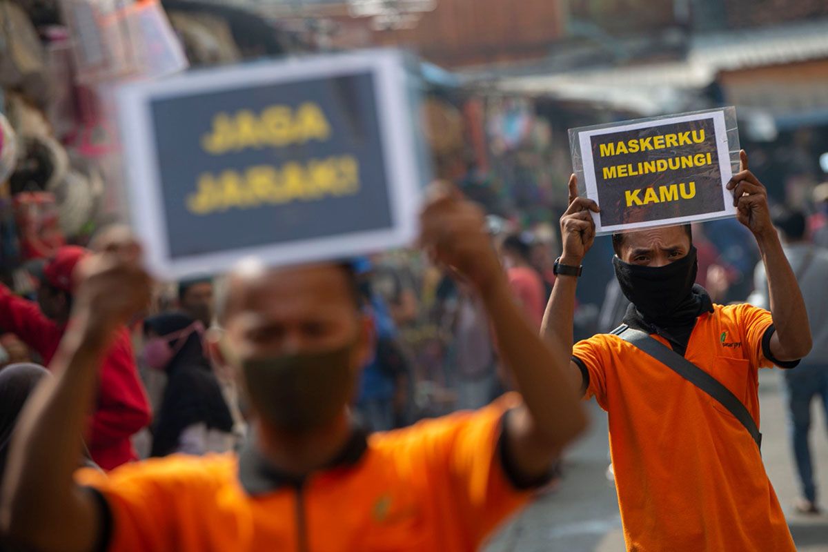 Petugas pengelola pasar melakukan sosialisasi pencegahan COVID-19 dengan membawa poster berisi pesan di Pasar Jatinegara, Jakarta, Kamis (11/6/2020). Upaya tersebut untuk meminimalisir kasus penularan atau penyebaran COVID-19 terjadi di pasar.