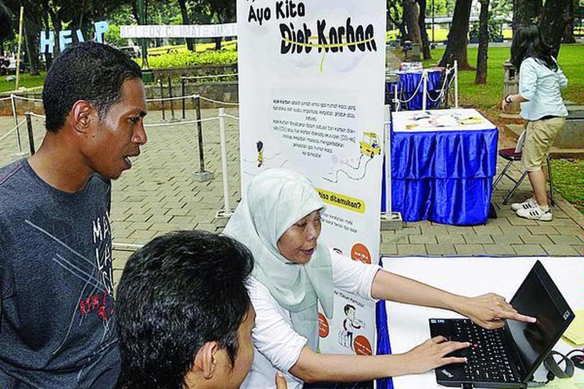 Staf Institute for Essential Service Reform,Musfarayani (duduk paling kanan), mewawancara Emanuel Herdianto (kiri) untuk menghitung jejak karbon Emanuel dalam Clinic Help-Climate Justice for Earth di Taman Suropati, Jakarta Minggu (25/4)