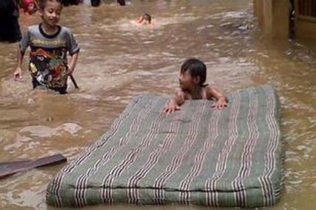 Anak-anak bermain di banjir yang merendam rumah mereka di Kelurahan Bukit Duri, Jakarta Selatan, Senin (24/12/2012). 