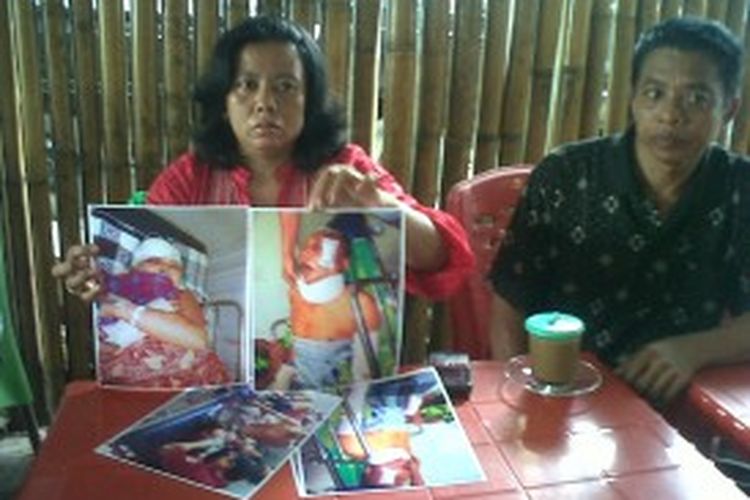 Hj Rahmatia (42) memperlihatkan foto kedua orangtuanya yang menderita luka parah setelah dikeroyok dua cucunya beserta kelima temannya.