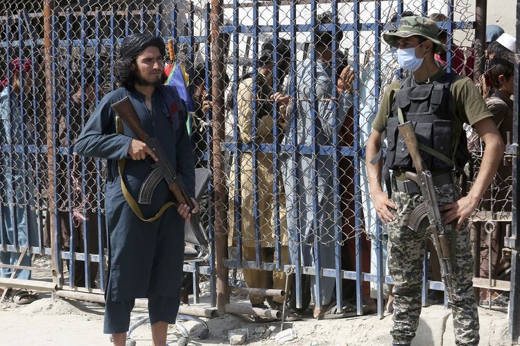 Paramiliter Pakistan (kanan) dan anggota Taliban (kiri) saat di titik penyeberangan antara Pakistan dan Afghanistan di Torkham, Pakistan, 21 Agustus 2021. Taliban pada Selasa (20/12/2022) melarang perempuan Afghanistan kuliah.