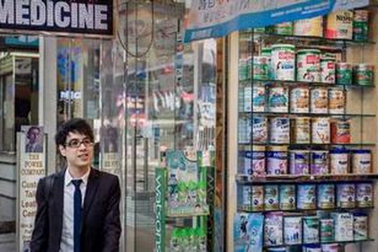 Seorang pria melintasi sebuah toko yang memajang berbagai merek susu formula untuk bayi. Hong Kong terancam mengalami kelangkaan susu formula karena diselundupkan ke China.