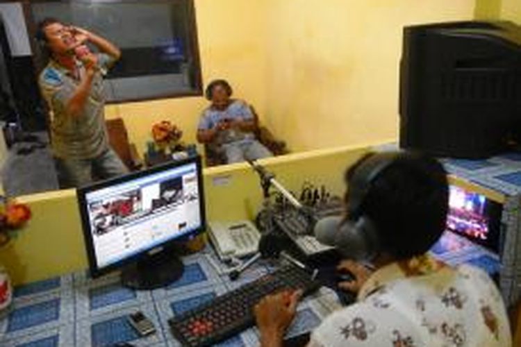 Salah satu pengunjung radio komunitas tengah mendendangkan lagi ala karaoke.