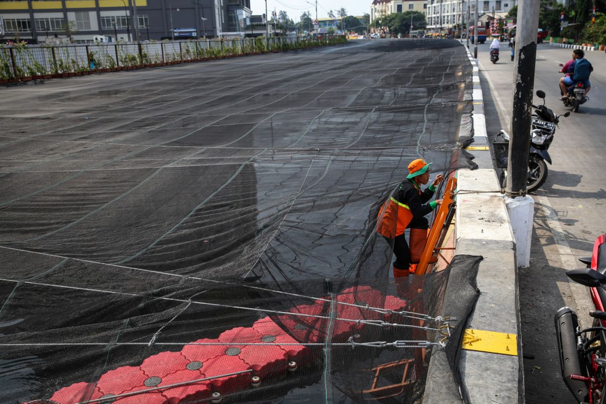 Pekerja memasang jaring-jaring untuk menutupi aliran Kali Sentiong atau Kali Item di Jakarta Utara, Jumat (20/7/2018). Pemasangan jaring-jaring berbahan nilon untuk mengatasi buruknya rupa Kali Item sebelum menerima para atlet Asian Games 2018 dari mancanegara yang akan menginap di Wisma Atlet.