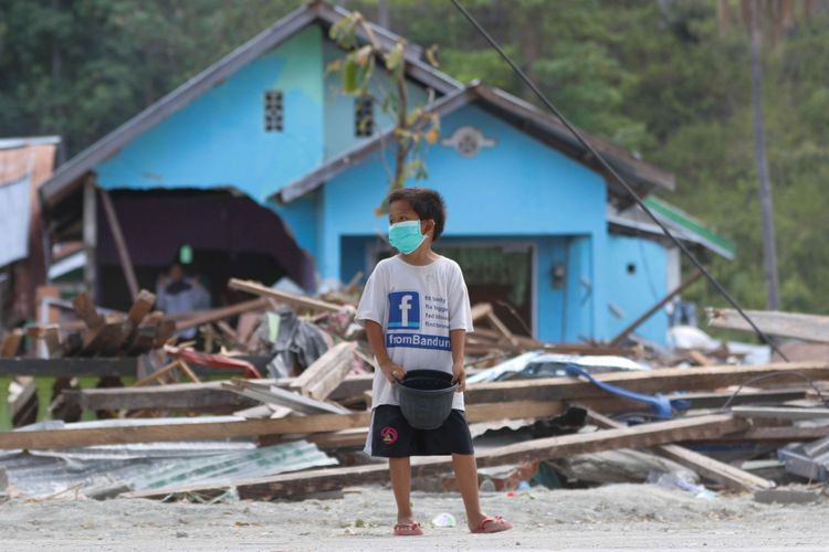 Bocah meminta bantuan di Desa Loli Saluran, Kecamatan Banawa, Kabupaten Donggala, Sulawesi Tengah, yang mengalami kerusakan pasca gempa dan Tsunami, Rabu (3/10/2018). Gempa yang terjadi di Palu dan Donggala mengakibatkan 925 orang meninggal dunia dan 65.733 bangunan rusak.