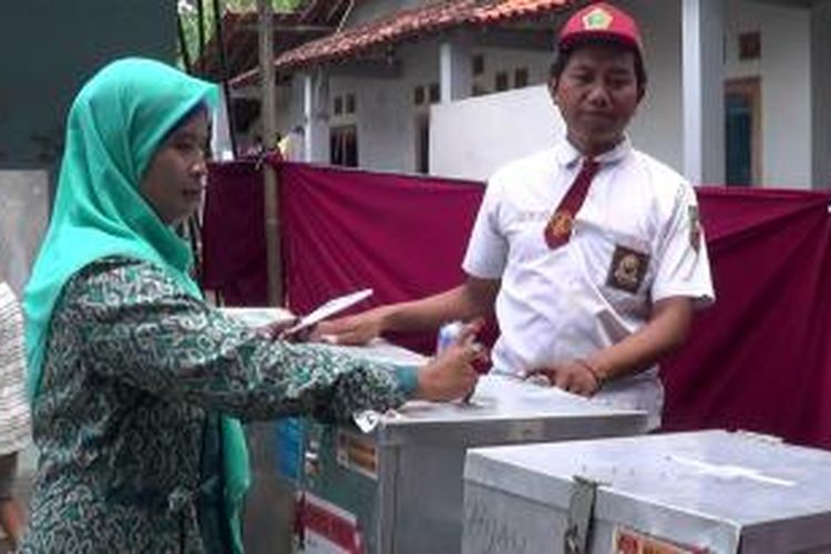 Salah seorang warga memasukkan kertas suara di TPS 01 Desa Bulusari, Bulakamba Brebes, Jawa Tengah. Seluruh petugas KPPS memakai seragam SD untuk menarik minat warga agar datang ke TPS


