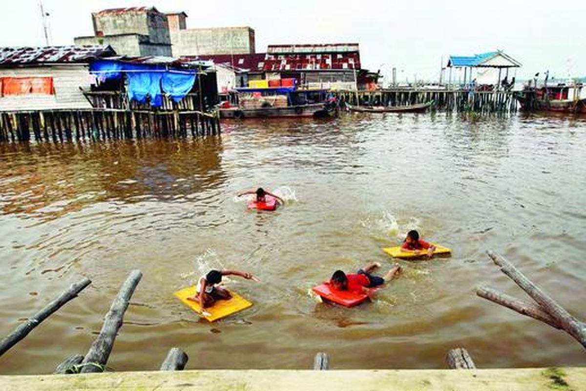 Anak-anak berenang di sekitar rumah-rumah panggung milik warga di Kampung Nelayan, Kuala Tungkal, Jambi, Rabu (9/2). Kampung Nelayan adalah sisa kawasan di Kuala Tungkal yang masih berdiri di atas air.
