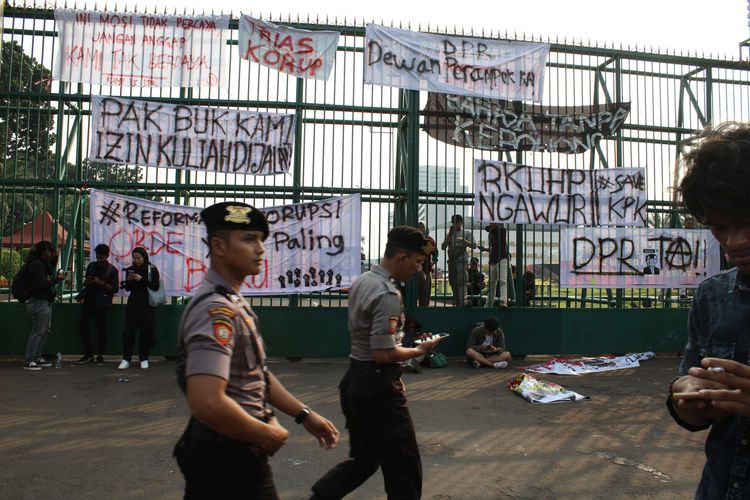 Personel Polisi melintas di tengah aksi demo di Depan Gedung DPR/MPR, Jalan Gatot Subroto, Senayan, Jakarta Pusat, Senin (23/9/2019). Ribuan mahasiswa yang turun aksi menolak pengesahan RKUHP.