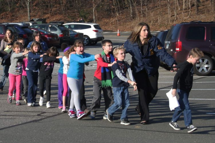 Polisi memimpin rombongan anak-anak keluar dari sekolah mereka, Sekolah Dasar Sandy Hook, di Connecticut, Amerika, setelah penembakan terjadi di sekolah itu, Jumat (14/12/2012).  