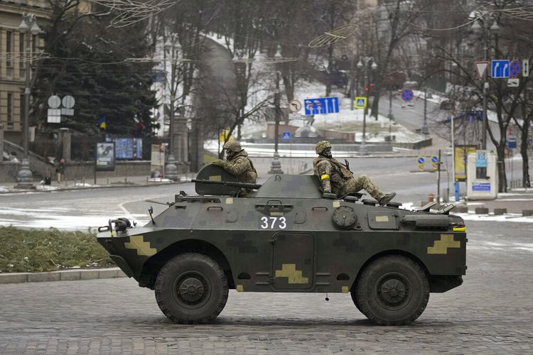 Prajurit Ukraina naik di atas pengangkut personel lapis baja yang melaju di jalan yang sepi selama alarm serangan udara, di Keiv, Ukraina, Selasa, 1 Maret 2022.