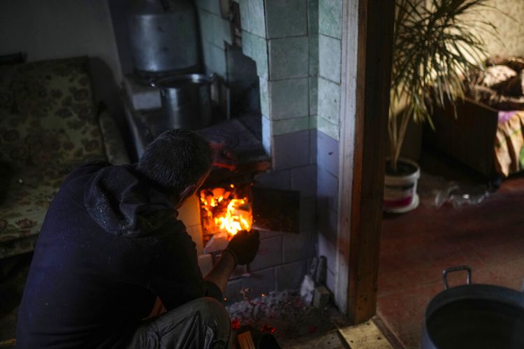 Viktor Palyanitsa menyalakan kayu di tungku di rumahnya di Kurylivka, Ukraina, Minggu, 16 Oktober 2022.