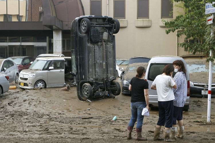 Sebuah mobil terbalik di jalanan berlumpur, usai diterjang banjir di Hitoyoshi, prefektur Kumamoto, Jepang, pada Minggu (5/7/2020). Hujan deras yang mengguyur wilayah Kumamoto mengakibatkan banjir besar dan tanah longsor, membuar puluhan orang terjebak di rumah-rumah dan bangunan lainnya.