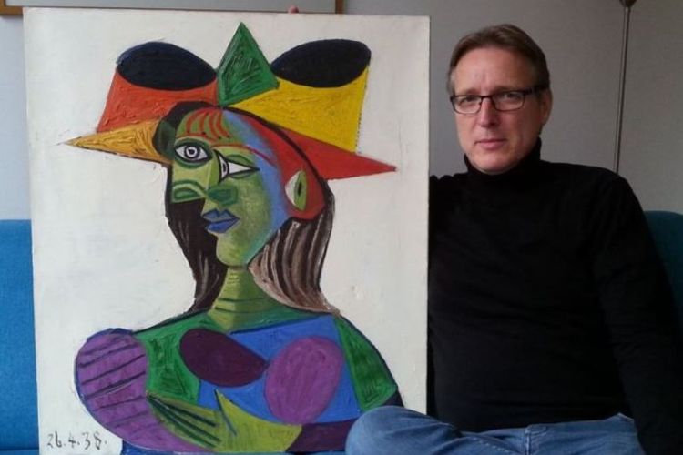 Detektif seni asal Belanda Arthur Brand berpose dengan lukisan Picasso Buste de Femme (Dora Maar) pada 14 Maret 2019 di rumahnya di Amsterdam, Belanda. (AFP)
