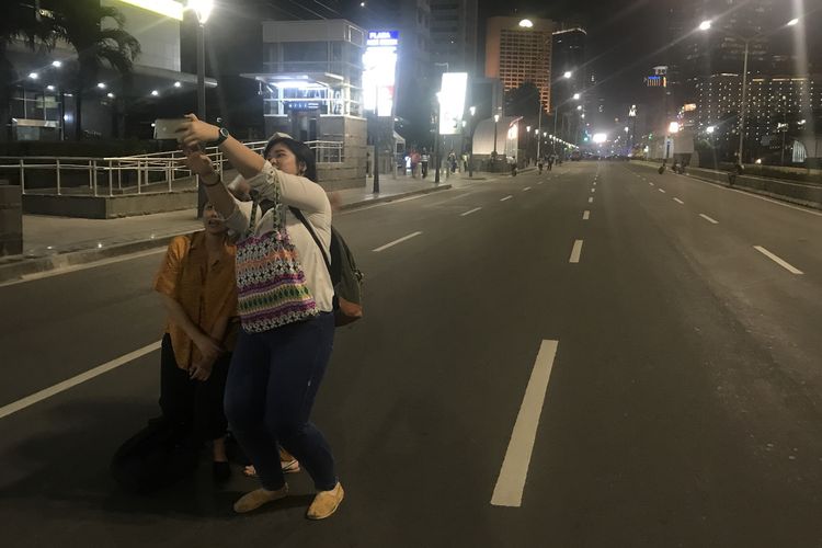 Sepulang kerja, warga yang bekerja di perkantoran di Jalan MH Thamrin hingga Bundaran HI melakukan selfie atau swafoto bersama dengan latar jalanan yang kosong dan sepi. Jalan itu belum dibuka oleh pihak kepolisian pasca-kericuhan pada 22 Mei 2019. Foto diambil Jumat (24/5/2019) malam. 