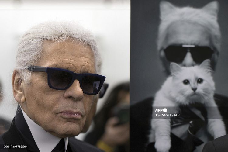 Perancang busana asal Jerman Karl Lagerfeld berpose di samping foto dirinya bersama kucingnya, Choupette pada 7 Februari 2014. Foto tersebut dipasang di ruang kerjanya di Chanel di Pantin, kawasan di luar Paris, Perancis. 