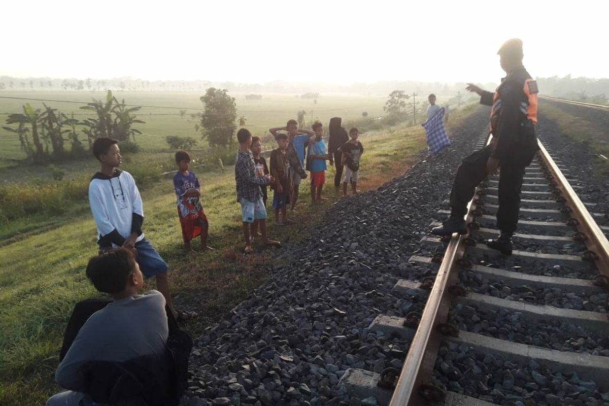 Petugas kereta api menghalau anak-anak bermain di jalur kereta api.