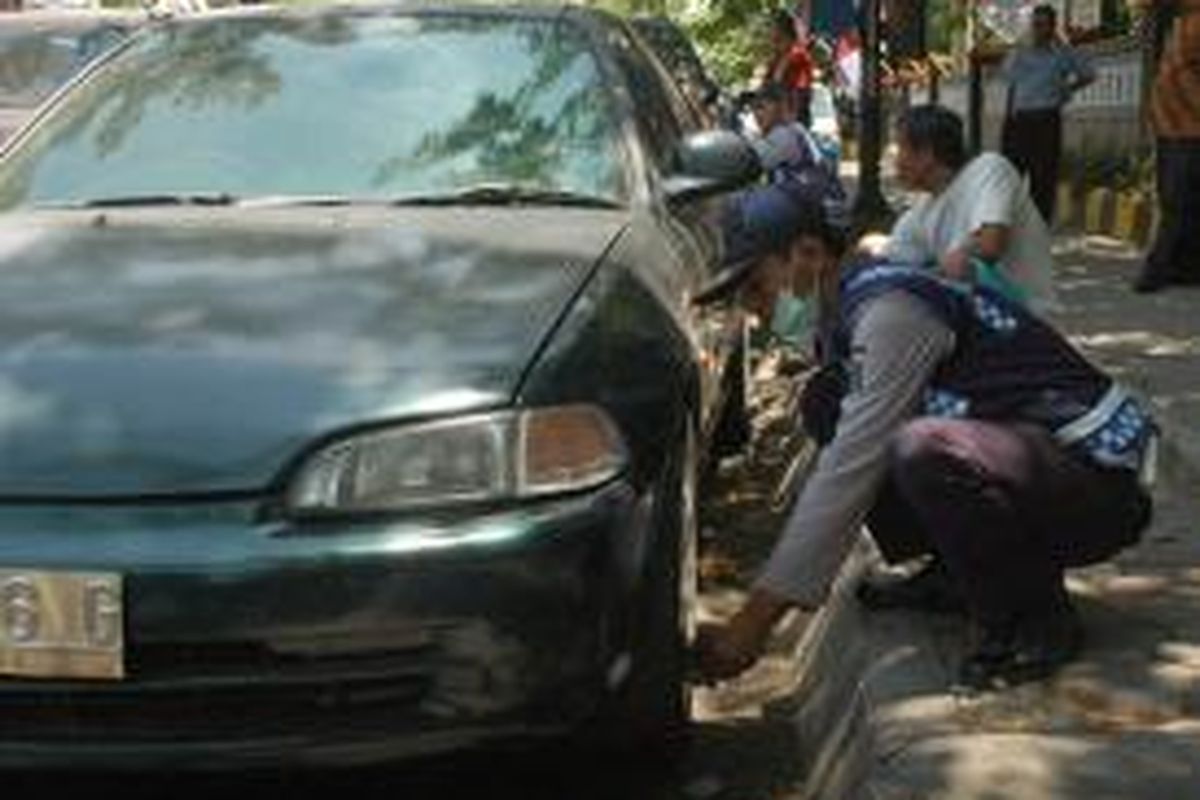 Petugas menggembosi ban mobil parkir sembarangan di Surabaya.