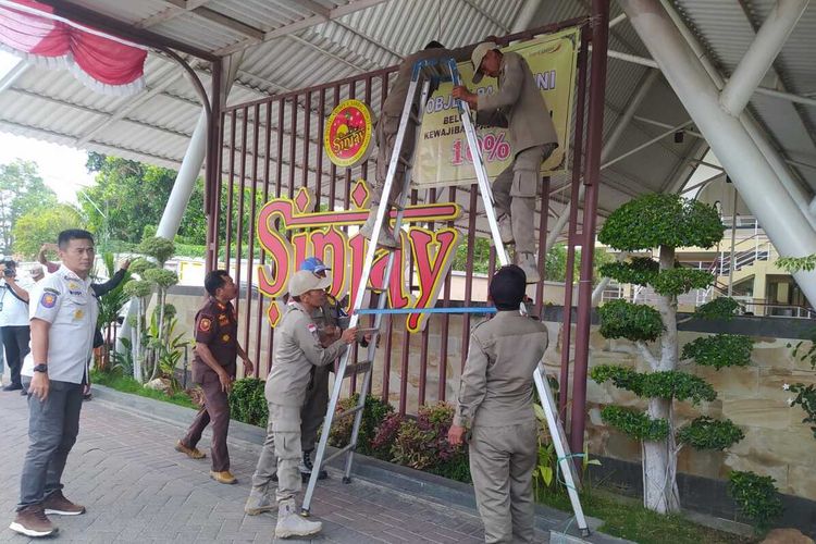 Satpol PP Bangkalan, Jawa Timur, memasang spanduk berisi imbauan pembayaran pajak 10 persen di RM Bebek Sinjay, Rabu (18/10/2023)