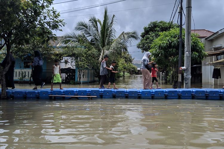 Warga menyebrang jembatan apung untuk melewati jembatan Alamanda yang terendam banjir setinggi 100 sentimeter di Periuk Kota Tangerang, Rabu (26/2/2020)