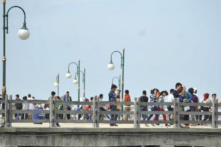 Pengujung menikmati pemandangan lepas pantai dari Dermaga Pantai Festival, Taman Impian Jaya Ancol, Jakarta Utara, Minggu (21/4/2013). Kawasan tersebut menjadi salah tempat pilihan warga Jakarta dan luar Jakarta yang ingin berwisata menikmati suasana pantai dengan nyaman. 