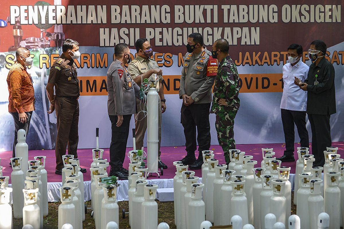 Gubernur DKI Jakarta Anies Baswedan (keempat kiri) didampingi Kapolda Metro Jaya Irjen Pol Mohammad Fadil Imran (ketiga kiri), Pangdam Jaya/Jayakarta Mayjen TNI Mulyo Aji (ketiga kanan) berbincang dengan Kapolres Jakarta Pusat Kombes Pol Hengki Haryadi (keempat kanan) saat penyerahan barang bukti tabung oksigen hasil pengungkapan kasus tindak kejahatan di Jakarta, Selasa (27/7/2021). Sebanyak 138 tabung yang sudah dilakukan pemeriksaan oleh Kementerian Kesehatan tersebut diserahkan kepada Pemerintah Provinsi DKI Jakarta untuk digunakan sebagai penanggulangan Covid-19 di sejumlah fasilitas pelayanan kesehatan di Jakarta.