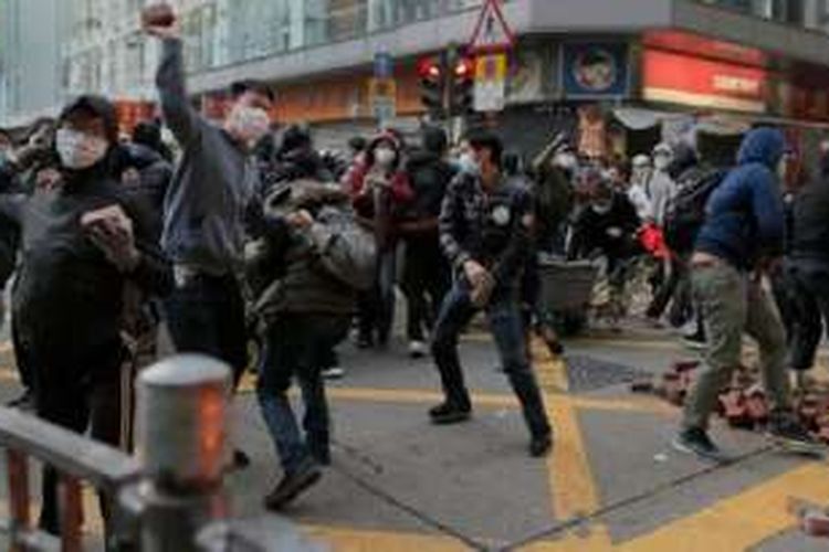 Demonstran melempar batu-bata dalam bentrokan dengan polisi di Hongkong, Selasa (9/2/2016) pagi. 