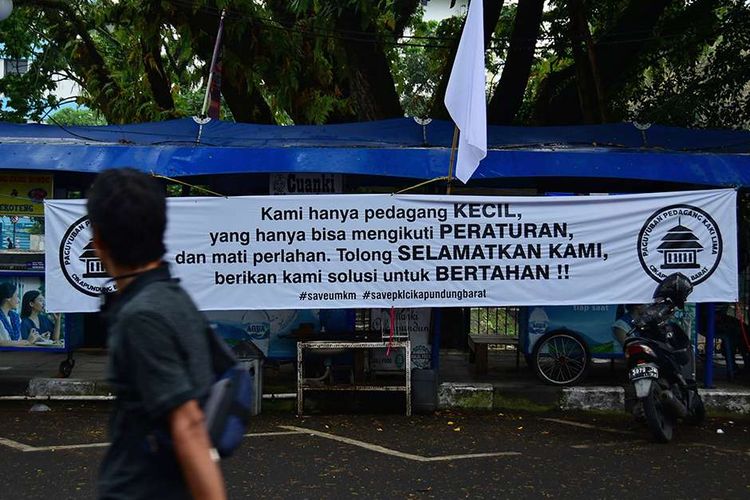 Pedagang kaki lima (PKL) yang berada di Jalan Cikapundung Barat, Kota Bandung, Jawa Barat, melakukan aksi pasang bendera putih di kios mereka, menyusul pemberlakuan PPKM Darurat, Senin (19/7/2021). Bendera putih yang dikibarkan 104 pedagang itu merupakan tanda mereka tak lagi sanggup menghadapi Covid-19 yang telah menghancurkan perekonomian.