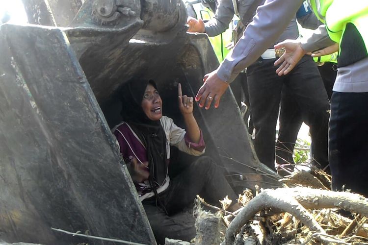 Seorang wanita menghadang ekskavator yang merobohkan pohon kelapa di pekarangan rumahnya, Kamis (28/6/2018). Ia sampai berani masuk ke bucket atau sendok besi ekskavator. PT Angkasa Pura dan PT PP melanjutkan pembersihan lahan yang akan digunakan untuk pembangunan bandara baru Yogyakarta di Kulonprogo.