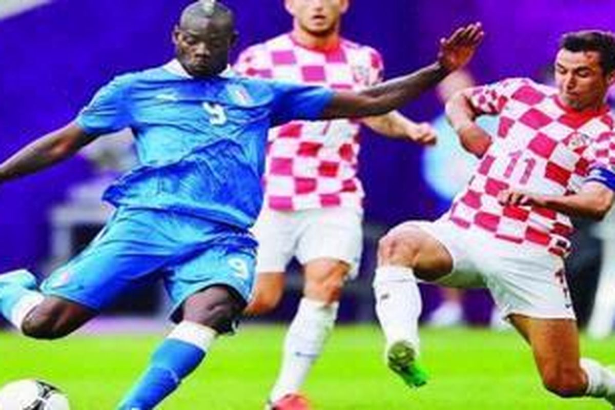 Striker Italia, Mario Balotelli (kiri), hendak dicegat oleh gelandang Kroasia, Darijo Srna, saat kedua tim berduel di Stadion Municipal, Poznan, Polandia, Kamis (14/6). Kedua tim bermain imbang 1-1 dalam laga Grup C tersebut.
