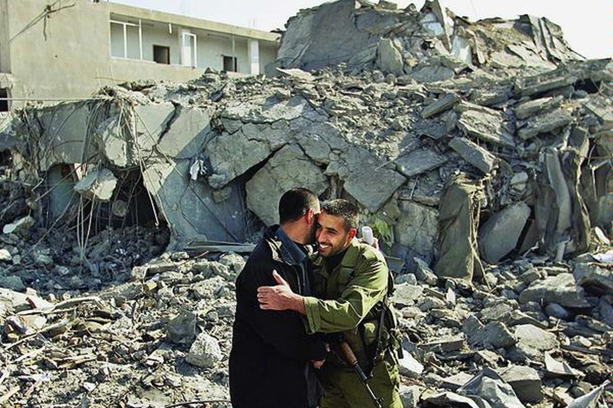 Pejabat polisi Hamas, Palestina, berpelukan di tengah puing-puing markas keamanan dan penjara pusat di Gaza City, Jalur Gaza, Rabu (21/1). Markas keamanan ini hancur akibat serangan udara Israel, akhir Desember lalu. Jalur Gaza relatif tenang menyusul gencatan senjata.  