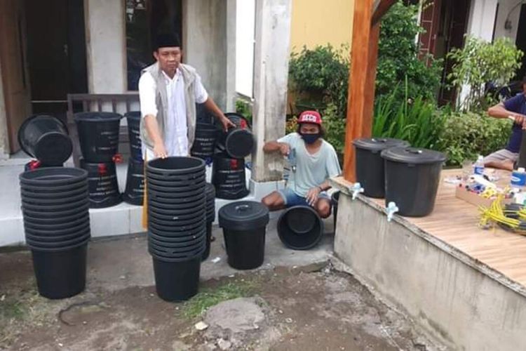 warga bergotong royong membuat tempat cuci tangan dari bahan ember dan kran air