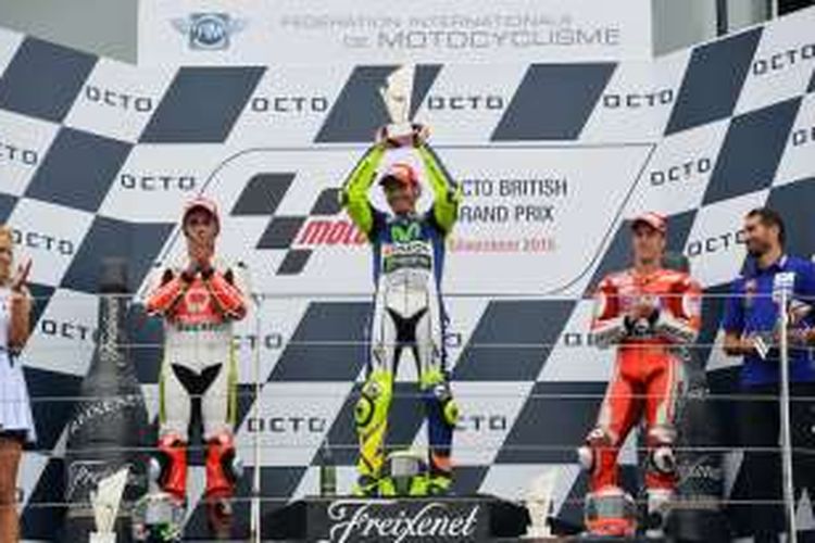 Pebalap Movistar Yamaha asal Italia, Valentino Rossi (tengah), mengangkat trofi juara setelah memenangi balapan GP Inggris di Sirkuit Silverstone, Minggu (30/8/2015. Pebalap Pramac Racing asal Italia, Danilo Petrucci (kiri) finis di urutan kedua, sementara pebalap Ducati yang juga berasal dari Italia, Andrea Dovizioso, finis di urutan keitga.