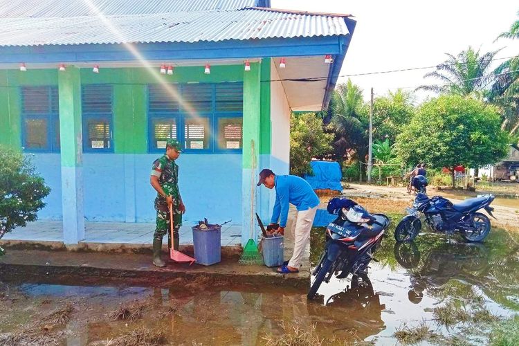 Prajurit TNI dan warga bergotong royong membersihkan lumpur sisa banjir di Desa Kasang Padang, Kecamatan Bonai Darussalam, Kabupaten Rokan Hulu, Riau, Sabtu (2/9/2023).