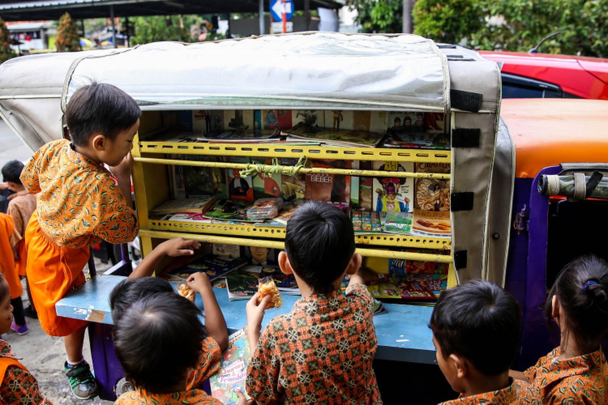 Anak-anak sekolah Paud saat membaca buku di bemo perpustakaan saat jam istirahat di Rusun Karet Tengsin, Jakarta, Jumat (7/12/2018). Pak Sutino (58) adalah sopir bemo yang merintis bemo tuanya menjadi perpustakaan keliling bagi anak-anak sejak tahun 2013.