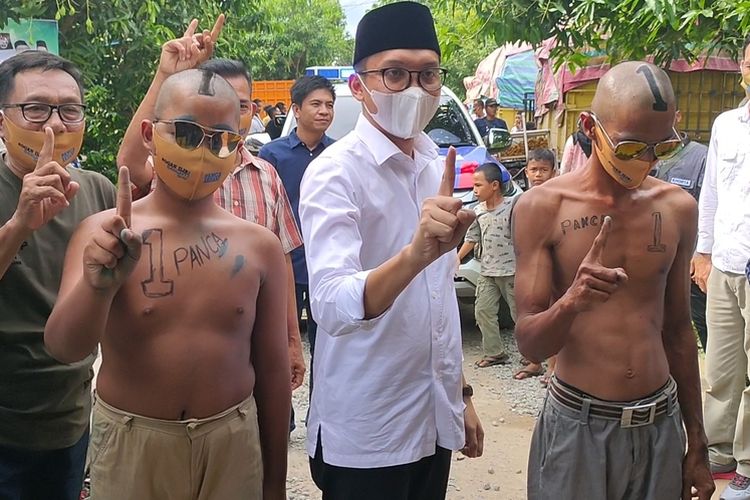 Calon Bupati Ogan Ilir nomor urut 1 Panca Mawardi Yahya berfoto bersama dua pemuda yang menjadikan tubuh mereka sebagai alat peraga kampanye (APK)