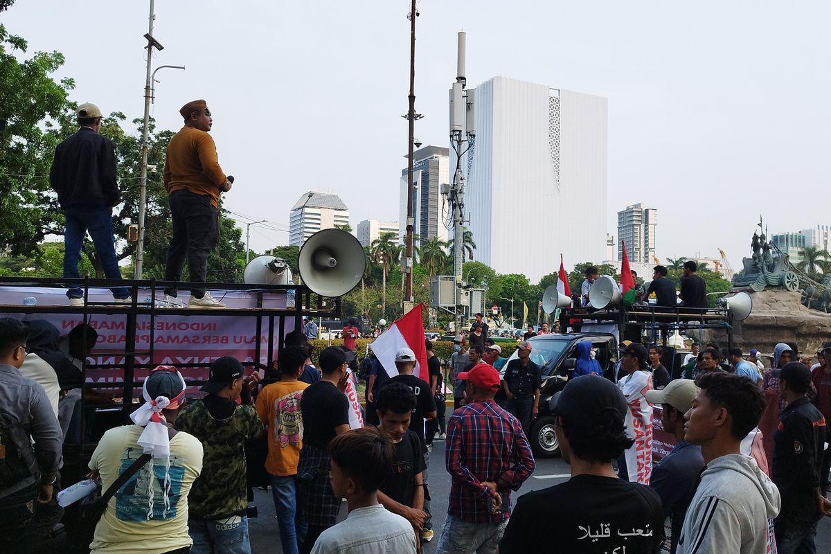Massa aksi mendengarkan jalannya sidang Majelis Kehormatan Mahkamah Kontitusi (MKMK) lewat pengeras suara di Patung Kuda, Gambir, Jakarta Pusat, Selasa (7/11/2023).
