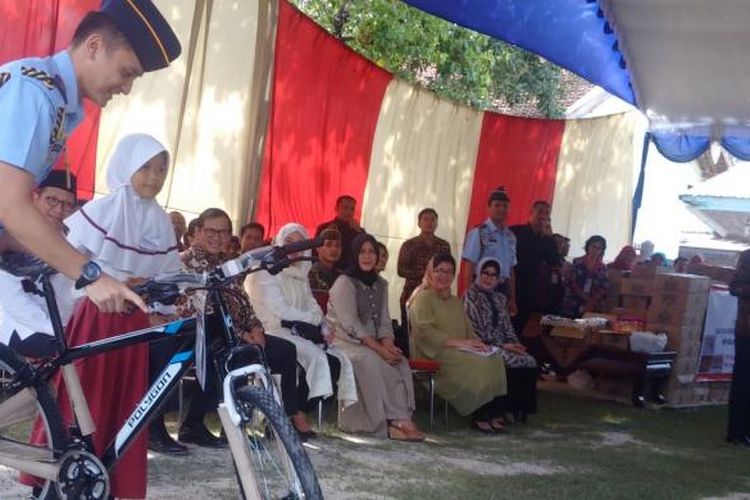 Tuntun sepeda-Ajudan Presiden Jokowi, Lettu Luqman menuntun sepeda hadiah untuk siswi sd kelas empat Sd Karangpatihan, Dina Wardani (berjilbab,red) setelah berhasil menjawab pertanyaan orang nomer satu di Indonesia itu, Senin (19/6/2016) sore. 