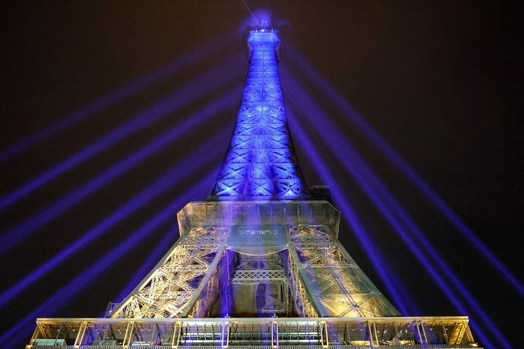 Sebuah foto memperlihatkan Menara Eiffel menyala dengan warna bendera Ukraina untuk menunjukkan dukungan kepada Ukraina, satu tahun setelah Rusia melancarkan invasi militer ke negara itu, di Paris, Kamis (23/2/2023). Kyiv ditetapkan pada 24 Februari untuk menandai ulang tahun pertama invasi Moskow, ketika Ukraina bersiap untuk kemungkinan serangan baru Rusia setelah setahun pembangkangan dan kesedihan, seperti setahun yang lalu, Presiden Rusia mengejutkan dunia dengan mengirim pasukan melintasi perbatasan pada dini hari untuk  de-militerisasi Ukraina, dalam langkah yang dilihat sebagai hukuman atas poros Kyiv ke Barat.