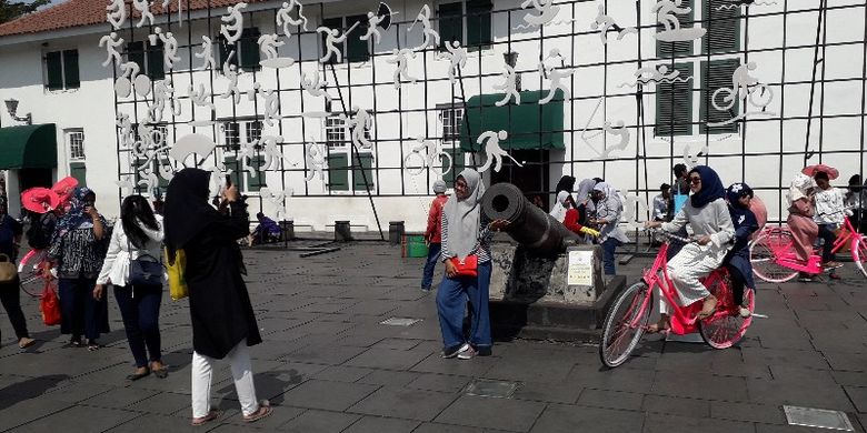 Pengunjung mengabadikan momen di salah satu meriam di Taman Fatahillah, Jakarta Barat yang menjadi bagian cagar budaya dari sejarah Kota Tua.