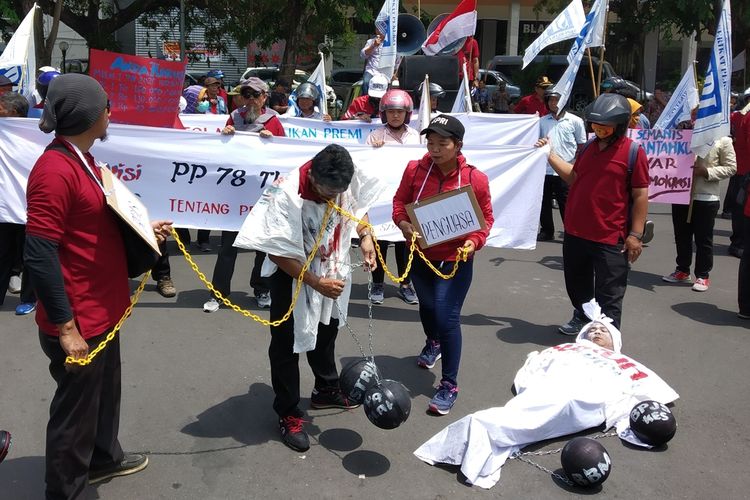 Teatrikal buruh dengan memakai kostum pocong menolak kenaikan premi BPJS Kesehatan yang mencapai 100 persen di depan Kantor DPRD Sukoharjo, Jawa Tengah, Rabu (13/11/2019).