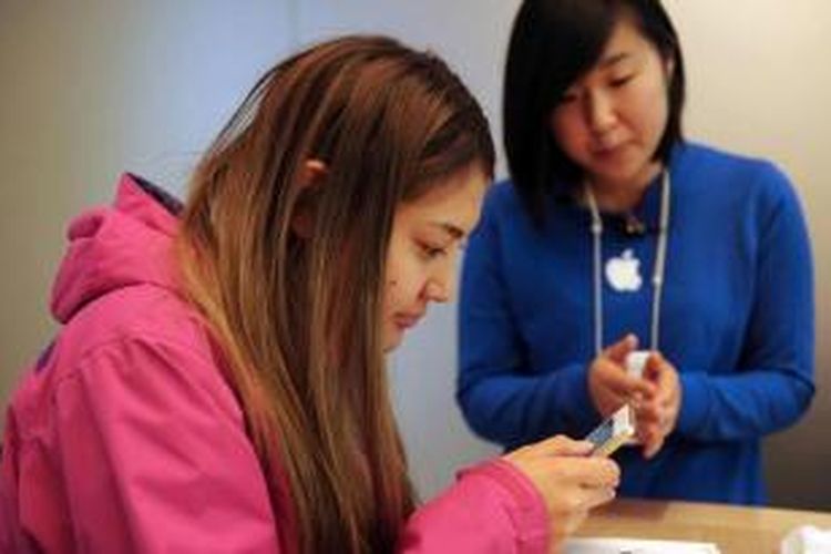 Seorang staf (kanan) membantu pembeli produk iPhone terbaru di Apple Store di Sydney, 20 September 2013. Apple resmi memasarkan produk terbaru iPhone 5s dan 5c ke seluruh dunia.