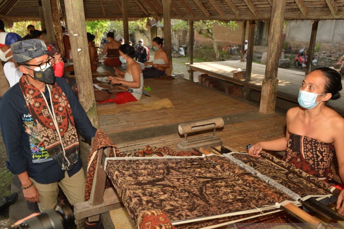 Menteri Pariwisata dan Ekonomi Kreatif (Menparekraf) Sandiaga Salahuddin Uno berbincang dengan perajin kain tenun di Desa Tenganan, Kabupaten Karangasem, Bali, Jumat (24/9/2021). 
