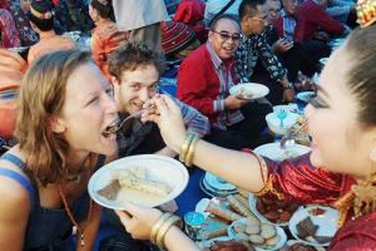Wisatawan mancanegara mengikuti acara makan bersama pekande-kandea di Keraton Buton, Kota Baubau, Sulawesi Tenggara, akhir Mei 2015. Dalam tradisi makan khas suku Buton ini, para tamu disuapi oleh gadis-gadis yang belum menikah sambil berpantun. 