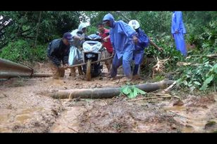 Warga di Gunung Paro, Aceh, membantu pengendara yang ingin melewati lokasi longsor dengan bayaran Rp 50.000 per motor, Senin (3/11/2014).