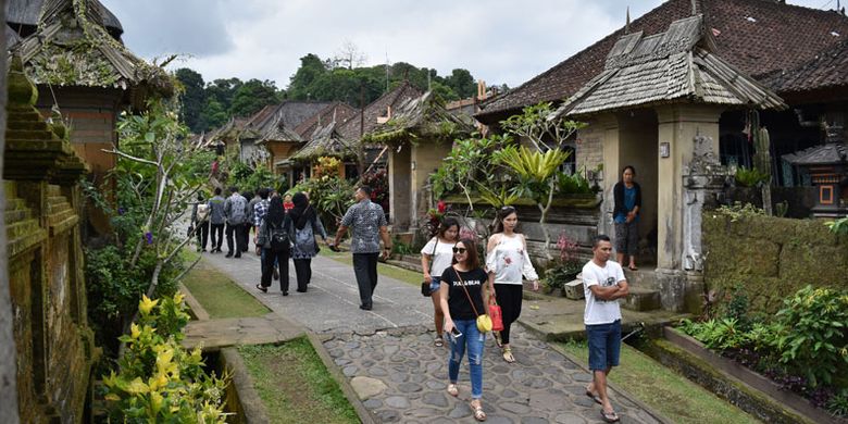 Sejumlah wisatawan mengunjungi Desa Adat Penglipuran di Kubu, Kabupaten Bangli, Bali, Kamis (19/7/2018). Desa yang telah berdiri sejak 700 tahun silam pada masa Kerajaan Bangli tersebut mendapat predikat dari TripAdvisor sebagai desa terbersih sedunia pada 2016 dan saat ini menjadi destinasi favorit wisatawan untuk menikmati suasana perkampungan tradisional adat khas Bali.